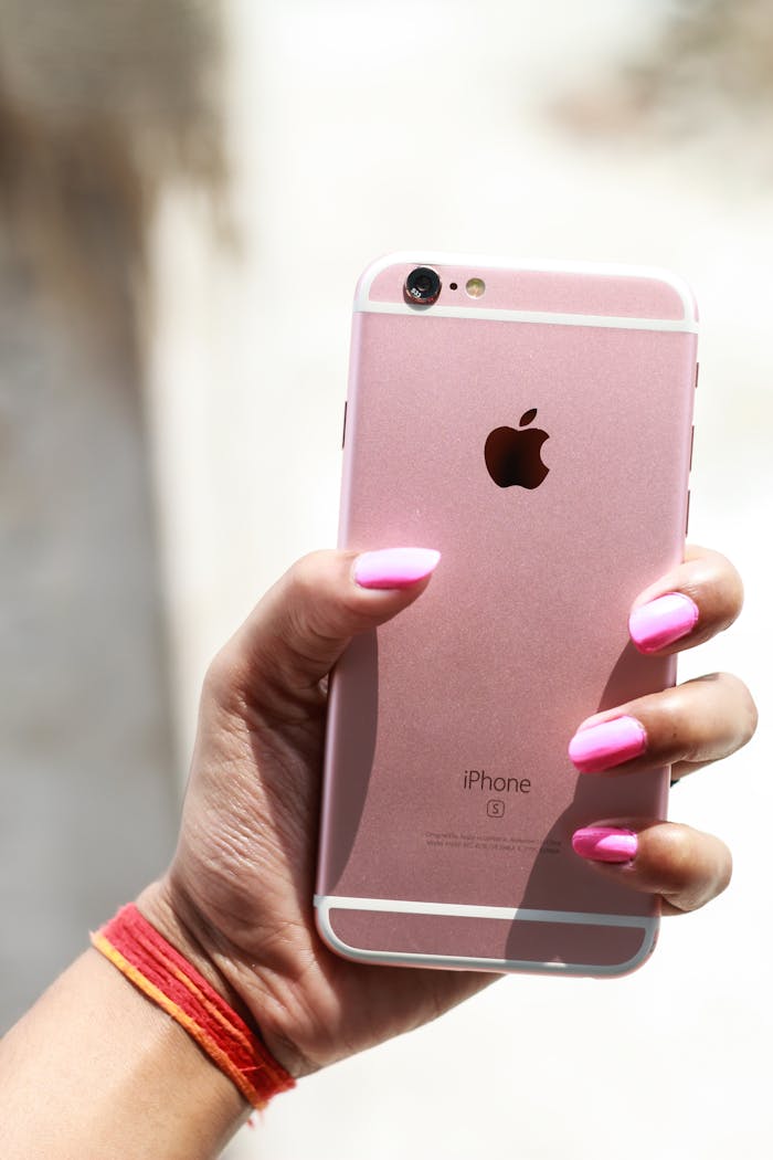 hero-img-02 Close-up of a hand holding a smartphone with a reflective back in a bright outdoor setting.